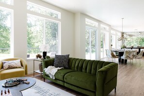 A spacious living area with a green sofa, a yellow armchair, and a dining table with chairs. - Emerald Acres, an elevated Retreat on Five Private Acres (Bellingham)