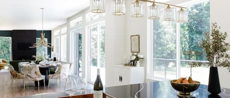 A modern kitchen with a marble countertop, a wine bottle, and a fruit bowl.