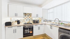 A modern kitchen with white cabinets, a built-in oven, a microwave, and a dishwasher. - 3 Bedroom Home with Private Garden in Newcastle (Whickham)