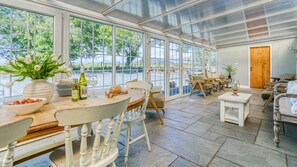A conservatory with a stone floor, large windows, and a wooden door. - The Lodge at Ynys - sleeps 20 guests  in 8 bedrooms (Nefyn)