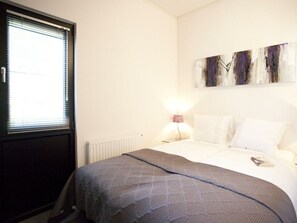 Ein Schlafzimmer mit einem Bett, einem Heizkörper, einem Fenster mit Jalousien und einem Wandbild.