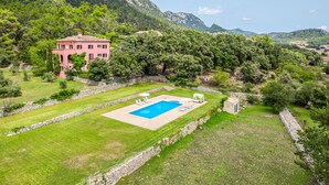 A large pink villa with a swimming pool, surrounded by lush greenery and mountains. - Holiday Villa 'Villa Son Perot' with Mountain Views, Private Pool and Wi-Fi (Orient)