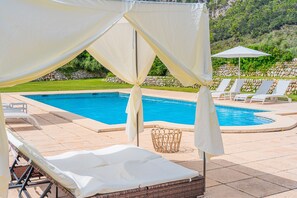 A pool area with lounge chairs, a canopy, and a wicker basket. - Holiday Villa 'Villa Son Perot' with Mountain Views, Private Pool and Wi-Fi (Orient)