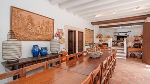A dining area with a long wooden table, chairs, and a large painting on the wall. - Holiday Villa 'Villa Son Perot' with Mountain Views, Private Pool and Wi-Fi (Orient)