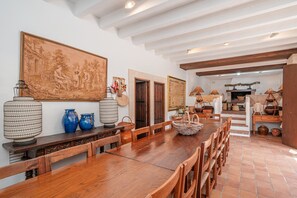 Un comedor con una larga mesa de madera, sillas y un cuadro grande en la pared.