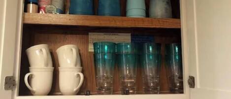 Un meuble contenant divers articles en verre et des gobelets en papier.