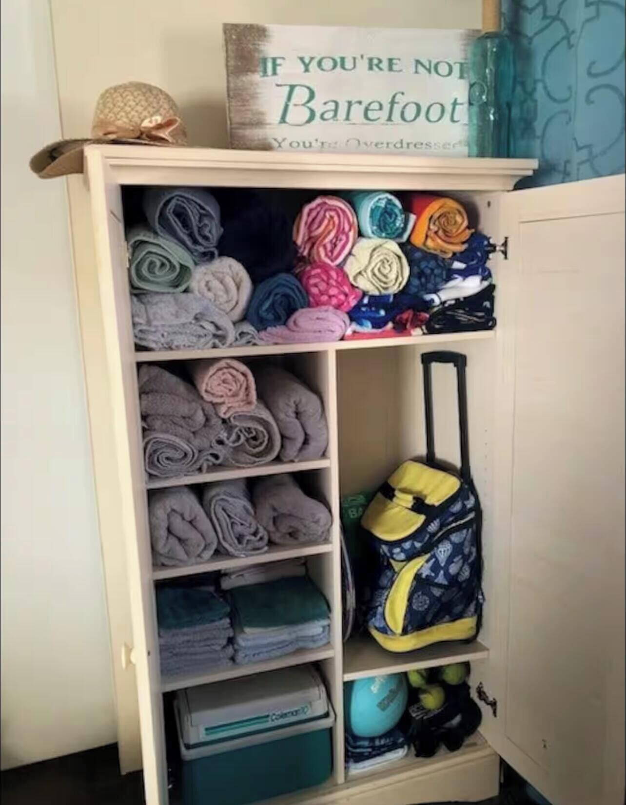 A wardrobe with folded clothes and a backpack.