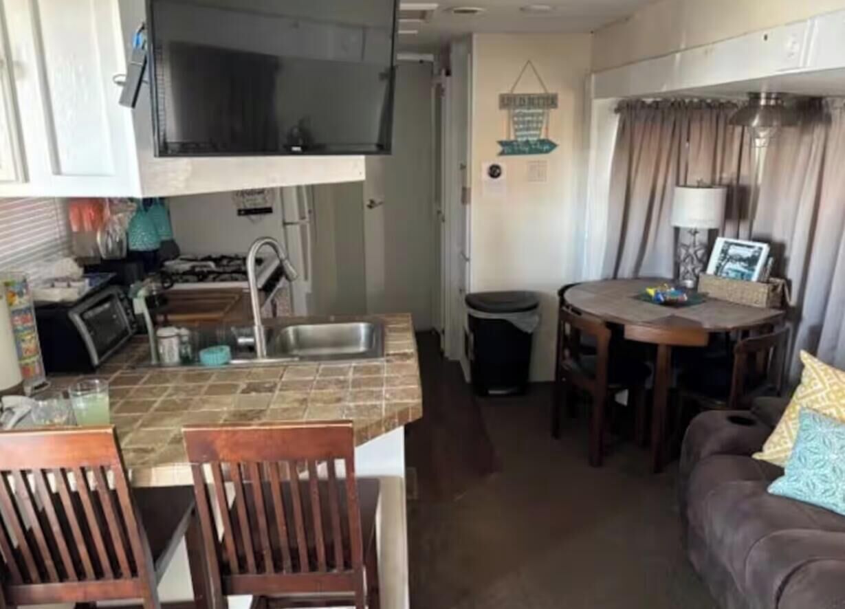 A compact kitchen with a microwave, sink, and dining area with chairs and a table.