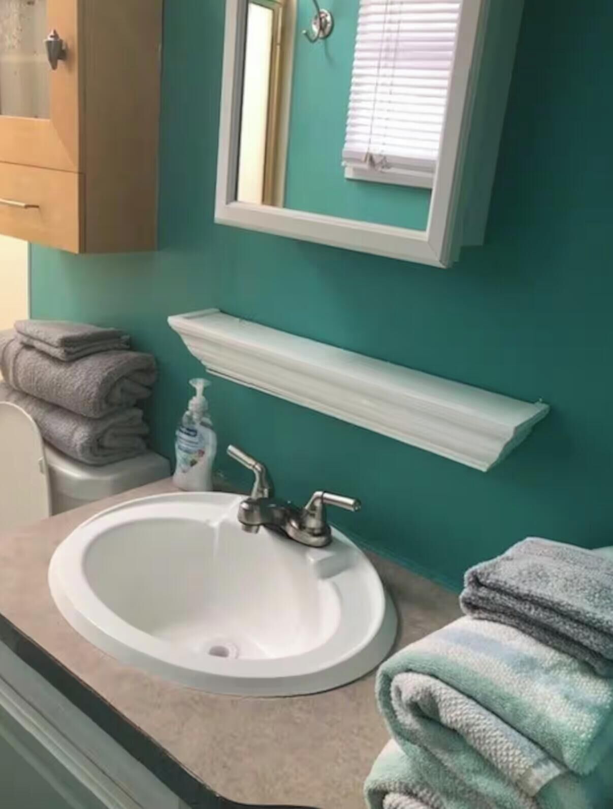 A bathroom with a white sink, a mirror, and a towel rack.