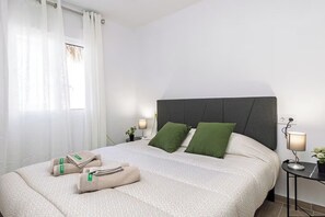 A neatly made bed with a patterned bedspread, two green pillows, and a folded towel on the bed. - 4. Monte Albán: Experience Agave Azul (Torrent)