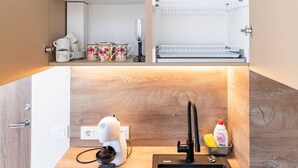 Eine kleine Küche mit Spüle, einer Kaffeemaschine und einem Regal mit Gläsern.