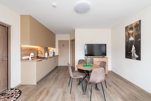 Eine moderne Wohnung mit Küche, Essbereich und Fernseher.