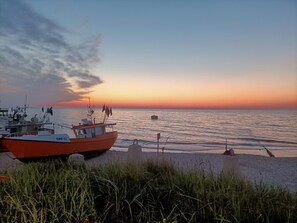 A boat docked at a pier with a clear view of the sunset over the water. - Year-round Holiday Home With Fireplace and Terrace (Mielno)