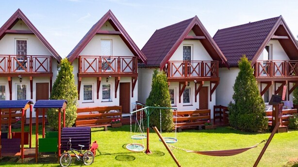 Een rij chalets met balkons, een gazon en buitenspeelplaats.