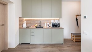 A modern kitchen with light-colored cabinets, a countertop, and a microwave.