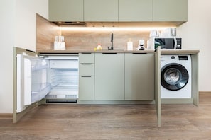 A compact kitchen with built-in appliances, including a dishwasher, a microwave, and a washing machine.