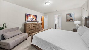 Una camera da letto con un letto, un divano, una cassettiera e un quadro appeso al muro.