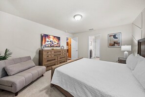 Ein Schlafzimmer mit Bett, Sofa, Kommode und einem Bild an der Wand.