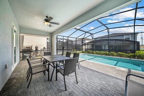 Überdachte Terrasse mit Pool, Gartenmöbeln und Blick auf angrenzende Häuser.