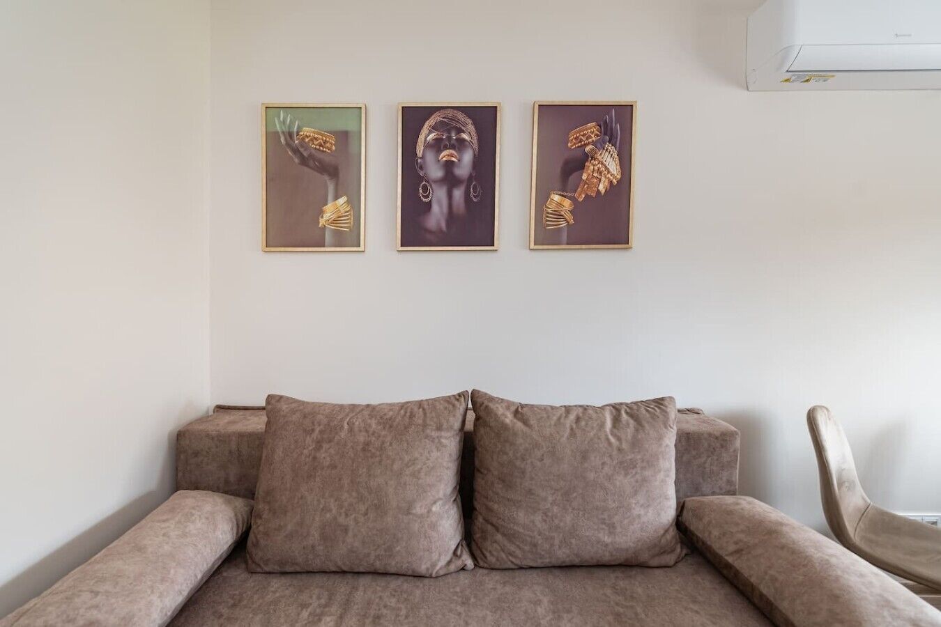 Ein Zimmer mit einer Couch, drei gerahmten Kunstwerken und einem Sessel.