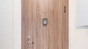 A wooden door with a numeric keypad, a doorbell, and a small window. - Medžiotojų apartment #3 by Polo Apartments (Naugardiškė)
