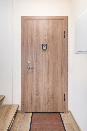 Eine Holztür mit einer Zifferntastatur, einem Klingelknopf und einem kleinen Fenster.