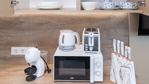 A kitchen with a microwave, toaster, kettle, and knife block on a wooden countertop.