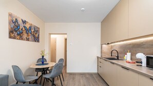 A modern kitchen with a wooden countertop, a sink, and a microwave. There is a dining area with a table and chairs.