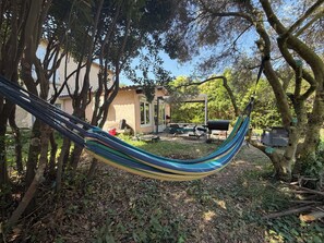 A hammock in a backyard with a house, outdoor furniture, and a barbecue grill. - Charming 2-bedroom townhouse with a garden, 15 minutes from Avignon. (Althen-des-Paluds)