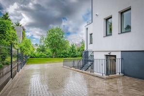 Moderni rakennus, jossa on kivetty sisäpiha, portaikko ja metalliaita.