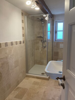 Eine Dusche mit Glastür, eine Badewanne und ein Fenster.