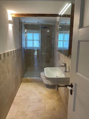 A bathroom with a glass-enclosed shower, a white sink, and a door with a brass handle. - New Store Opening! M6 - Anno 1802 - A Premium Getaway with Direct Access to Bamberg (Stegaurach)
