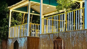 A two-story building with a covered outdoor area, wooden walls, and a paved entrance.