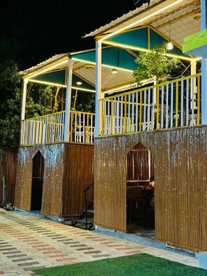 A two-story building with a covered outdoor area, wooden walls, and a paved entrance.