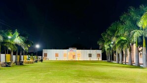 A building with a flat roof, a central entrance, and a paved area in front. - Kanha Green (Bhopal)
