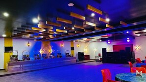 A spacious indoor venue with a stage, tables, and chairs arranged for events. - Kanha Green (Bhopal)