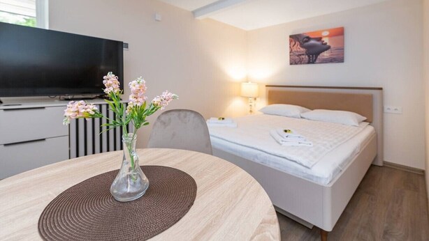 Une chambre d’hôtel avec un lit, une télévision, un vase de fleurs et un tableau au mur.