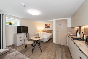Ein kleines Hotelzimmer mit Bett, Nachttisch, Lampe und Fernseher.
