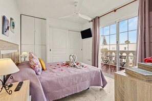Een hotelkamer met een bed, een televisie, een balkon met een tafel en stoelen, en uitzicht op de omgeving.