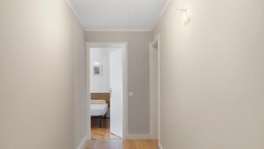 A narrow hallway with wooden flooring and a rug, leading to a bedroom with a bed and a nightstand. - Apartment 'Isola' with Mountain View, Private Terrace and Wi-Fi (Feltre)