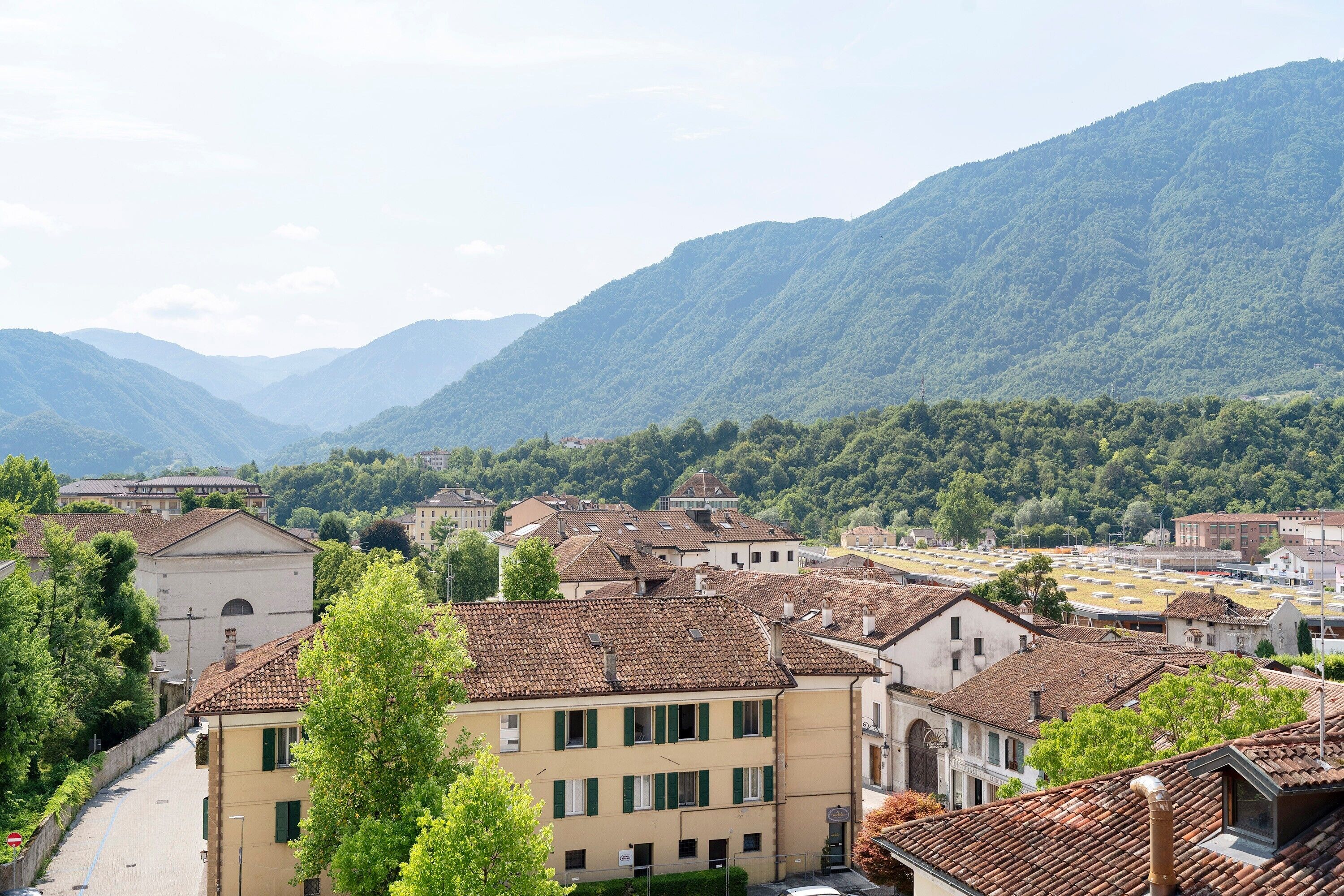 A town with traditional architecture, a street lined with buildings, and mountains in the background.
