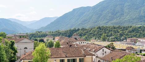 A town with traditional architecture, a street lined with buildings, and mountains in the background.
