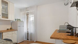 A compact kitchen with white cabinets, a wooden countertop, a sink, and a refrigerator. - Apartment 'Isola' with Mountain View, Private Terrace and Wi-Fi (Feltre)