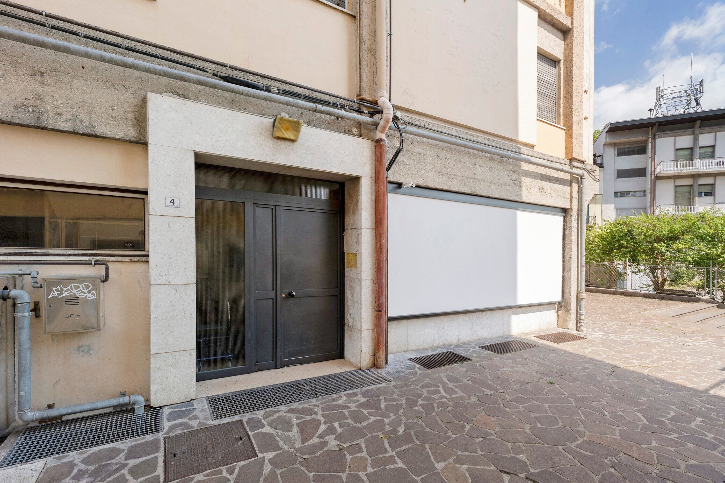 A building with a closed black door, a white garage door, and a stone-paved entrance.