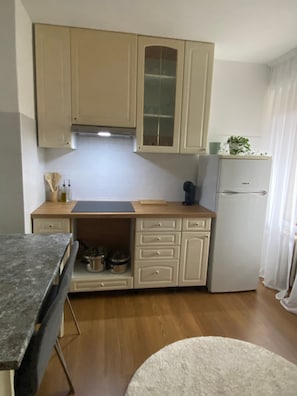 Una cucina compatta con mobili in legno, forno integrato e piano di lavoro con utensili da cucina.