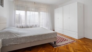 A bedroom with a bed, a wardrobe, and a window with sheer curtains. - Apartment 'Isola' with Mountain View, Private Terrace and Wi-Fi (Feltre)