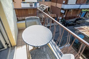 A balcony with a round table and chairs, a metal railing, and a view of the street below. - At the Court of the Gods - Zeus's Chamber (Tropea)