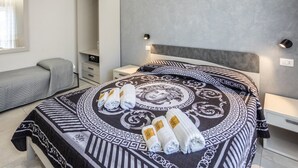 Ein modernes Hotelzimmer mit einem großen Bett, einem Nachttisch, einem Kleiderschrank und einer Bank.