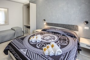 A modern hotel room with a large bed, a bedside table, a wardrobe, and a bench. - At the Court of the Gods - Zeus's Chamber (Tropea)