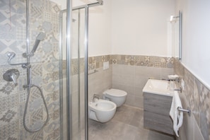 Een badkamer met een douche, toilet, bidet en wastafel.